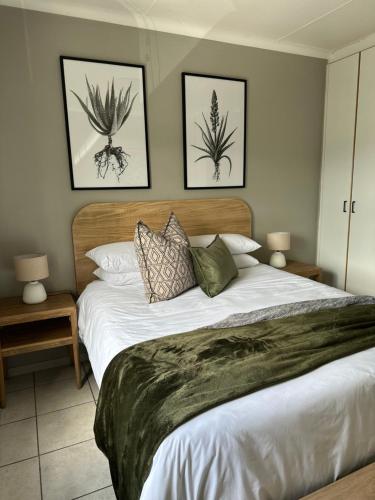 a bedroom with a large bed with two pictures on the wall at Lang Apartment in Great Brak River