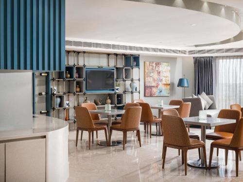 a dining room with tables and chairs and a tv at Novotel Vijayawada Varun in Vijayawāda