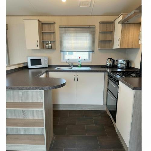 a kitchen with white cabinets and a counter top at Comfortable 3-Bed Caravan - Combe Haven in Hollington