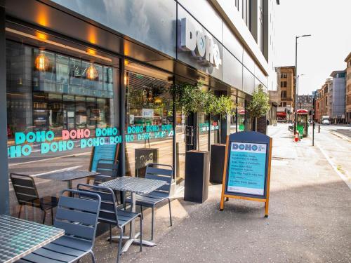 a cafe with tables and chairs in front of a store at ibis Styles Glasgow Central in Glasgow