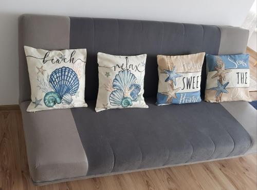 a gray couch with four pillows on it at Brzeziny Dworska 24 in Gdańsk