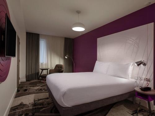 a bedroom with a white bed and a purple wall at ibis Styles Glasgow Central in Glasgow