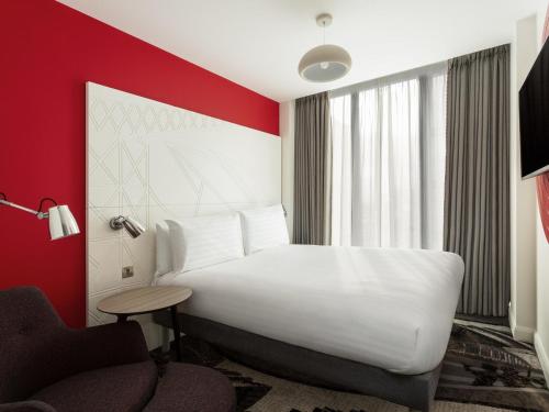 a hotel room with a white bed and a red wall at ibis Styles Glasgow Central in Glasgow