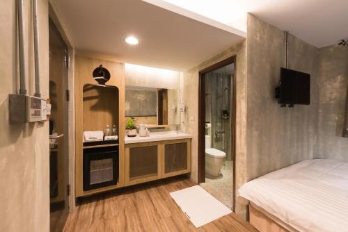 a bedroom with a bed and a bathroom with a sink at Beimen WOW Poshtel in Taipei