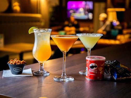 three cocktails sitting on a table with a can of soda at ibis Styles Glasgow Central in Glasgow