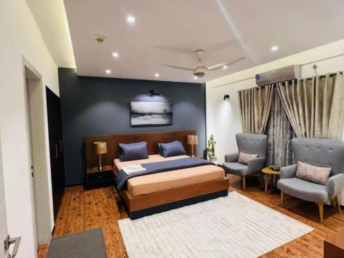 a bedroom with a bed and two chairs at Luxury 1 BHK Family Apartment in Bahria Town, Islamabad in Rawalpindi