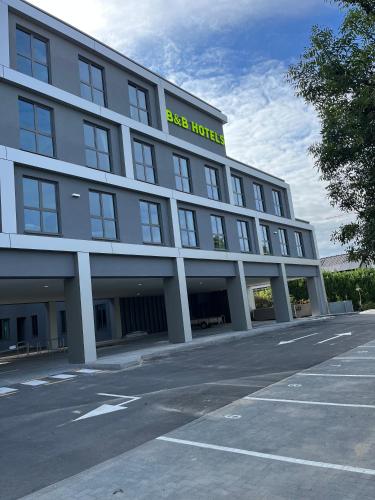a large white building with a yellow sign on it at B&B HOTEL Brussels Airport in Diegem