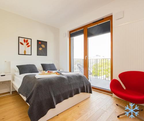 een slaapkamer met een bed en een rode stoel bij ShortStayPoland Zdziechowskiego in Warschau