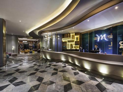 a lobby of a hotel with a man sitting at a desk at Mercure Shanghai Jiuting in Shang-hai