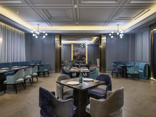 a restaurant with tables and chairs in a room at Mercure Shanghai Jiuting in Shang-hai