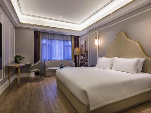 a bedroom with a large white bed and a window at Mercure Shanghai Jiuting in Shang-hai