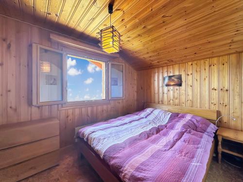 a bed in a wooden room with a window at Bear Ridge Retreat - 8mns to slopes - Swiss Alps in Agettes