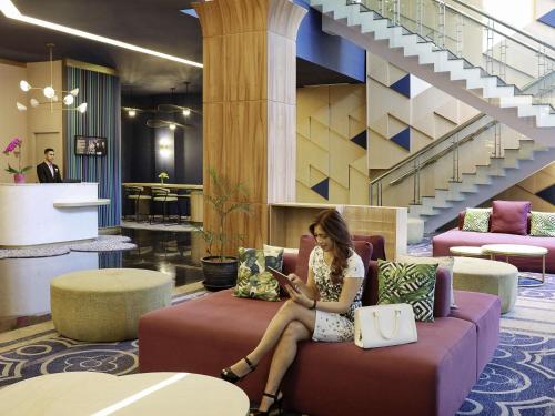 a woman sitting on a couch in a lobby at Mercure Bandung Nexa Supratman in Bandung