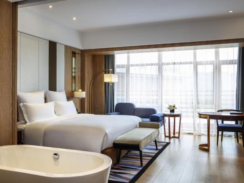 a hotel room with a bed and a bath tub at Pullman Changbaishan Resort in Fusong
