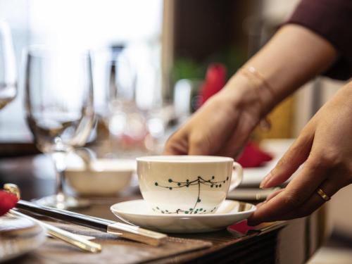 a person holding a coffee cup on a table at Pullman Changbaishan Resort in Fusong