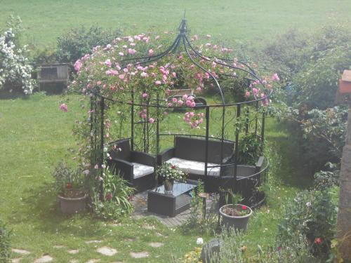 a garden with a gazebo with flowers and plants at Chambre D'hôtes Myrtille in Usson-en-Forez
