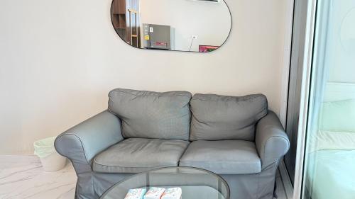 a living room with a gray couch and a mirror at Artisan Ratchada Condo Bangkok in Bangkok