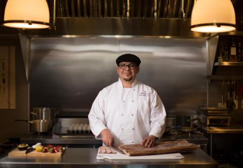 a chef standing in a kitchen holding a piece of bread at Enchante Boutique Hotel in Los Altos