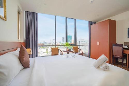a bedroom with a large white bed with a large window at Quoc Cuong Hotel & Apartment Danang by Haviland in Da Nang