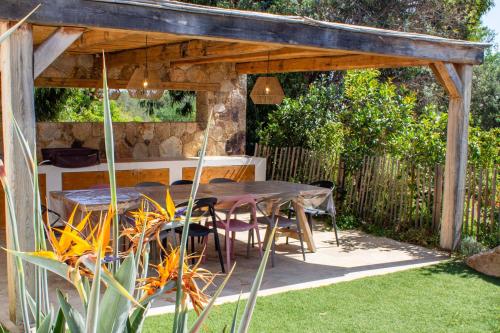 a table and chairs under a wooden pergola at Villa A Calia di Fiori Mare in Sainte-Lucie de Porto-Vecchio