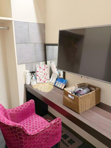 a pink chair sitting next to a desk with a tv at Hotel Plaisir Akihabara in Tokyo