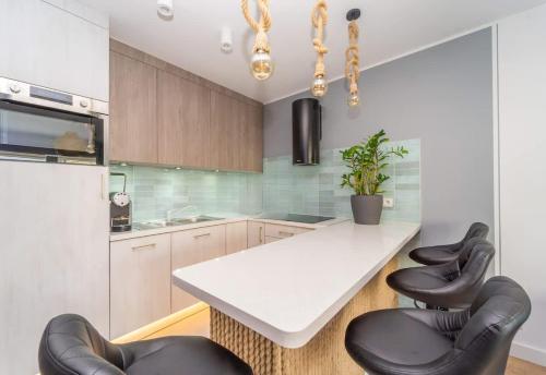 une cuisine avec une table blanche et des chaises noires dans l'établissement Bright and Blue 3city Apartment with Balcony in Gdynia by Noclegi Renters, à Gdynia