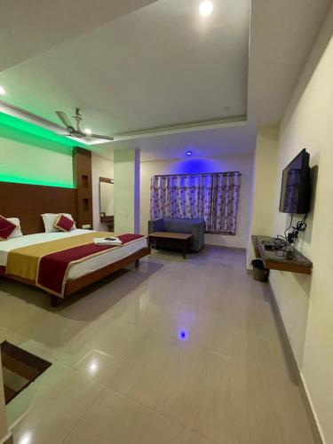 a bedroom with a bed and a couch and a television at Meridian castle in Puducherry
