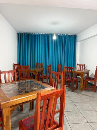 une salle à manger avec des tables et des chaises en bois et des rideaux bleus dans l'établissement Sonthos Hotel, à Nuwara Eliya