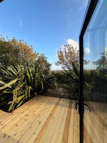 a glass door leading to a deck with plants at The Timber Lodge - Sennen Holiday Home in Sennen