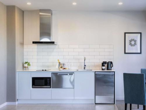 a white kitchen with a sink and a microwave at The Sebel Auckland Manukau in Auckland