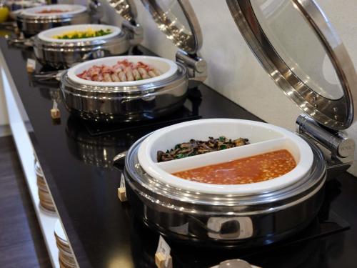 a row of pots filled with different types of food at The Sebel Auckland Manukau in Auckland
