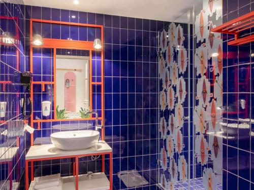 a blue tiled bathroom with a sink and a mirror at ibis Styles Warszawa Centrum in Warsaw