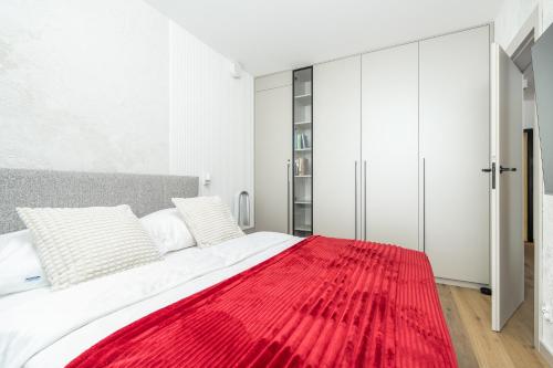 a bedroom with a red blanket on a bed at Sarbinove City Apartments in Sarbinowo