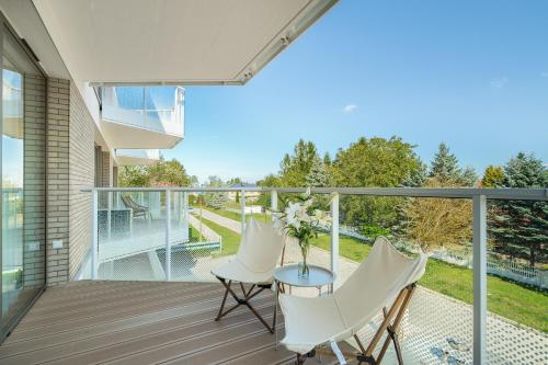 a balcony with white chairs and a table with a vase of flowers at Sarbinove City Apartments in Sarbinowo