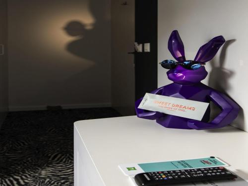 a purple bunny sitting on a table next to a remote control at ibis Styles Lausanne Center MadHouse in Lausanne