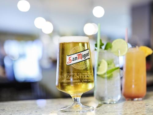 a glass of beer sitting on a table with a drink at Mercure Newbury West Grange Hotel in Thatcham
