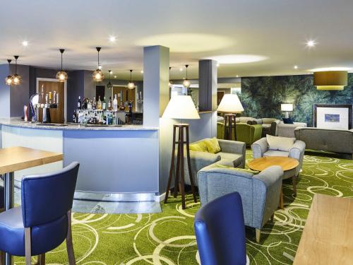 a hotel lobby with a bar and tables and chairs at Mercure Newbury West Grange Hotel in Thatcham