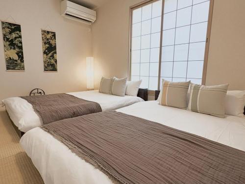 two beds in a room with a large window at Casa Stella 18 by Liaison in Osaka