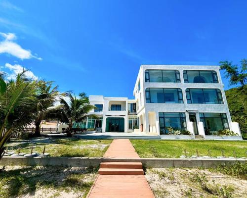 a large white building with palm trees in front of it at Nirvana Seaview Homestay in Wanning