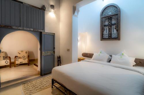a bedroom with a large white bed and a chair at Riad Tchaikana in Marrakech