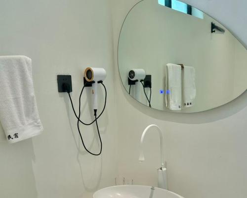 a white bathroom with a mirror and a sink at Nirvana Seaview Homestay in Wanning