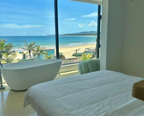 a bedroom with a tub and a view of the beach at Nirvana Seaview Homestay in Wanning