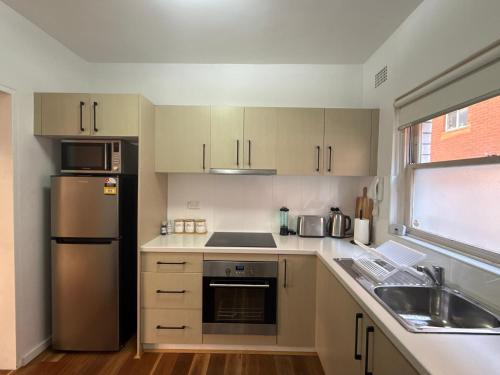 a small kitchen with a sink and a refrigerator at Randwick Shared Apt with Study Desk & Parking in Sydney