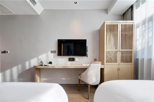 a room with a desk and a tv on a wall at Floral Hotel Yunkexuan in Datong