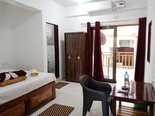 a bedroom with a bed and a desk and a table at Prakash Holiday Inn in Arambol