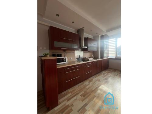 a kitchen with brown cabinets and a wooden floor at Wine Apartment 5 min to Old Town Gdańsk in Gdańsk