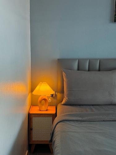 a lamp on a night stand next to a bed at Reboot Retreat Beach Resort, Restaurant, and Coffee Shop in Ban Talat Bang San