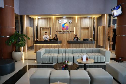 a lobby with couches and a bar with people at De Balen Soultan Hotel in Puyung