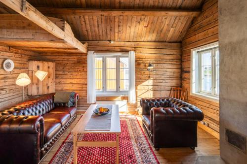 a living room with leather couches and a table at Sakrisøy Rorbuer in Reine