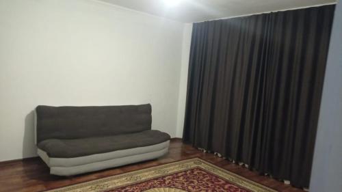 a living room with a couch and a window at Двухкомнатная квартира in Aktobe